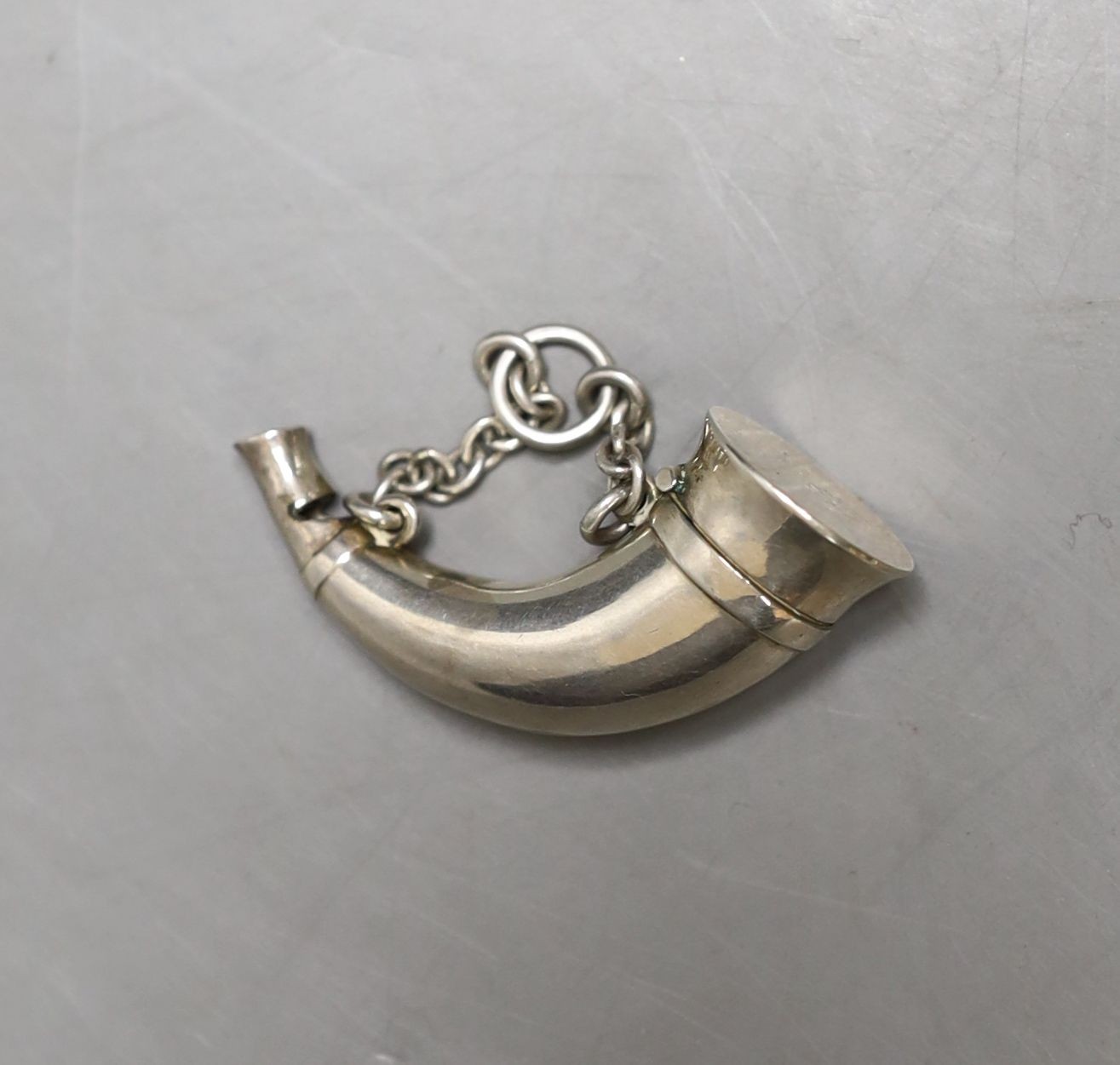 A late Victorian white metal novelty combination vinaigrette/whistle, modelled as a hunting horn, by Sampson Mordan & Co, 48mm.
